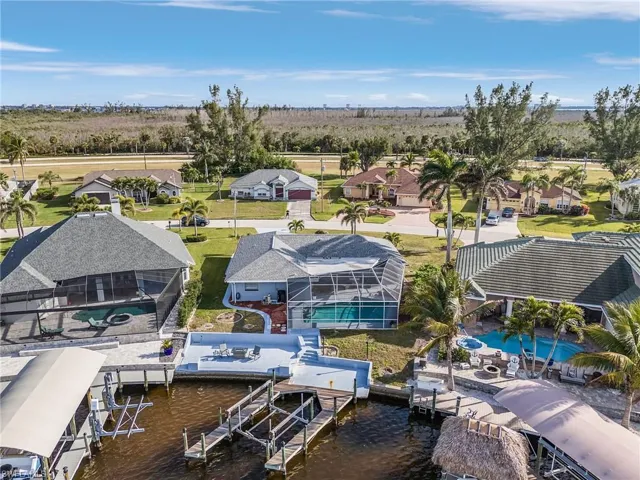 Waterfront property featuring a screened-in pool, private dock, boat lift, and a spacious sun deck