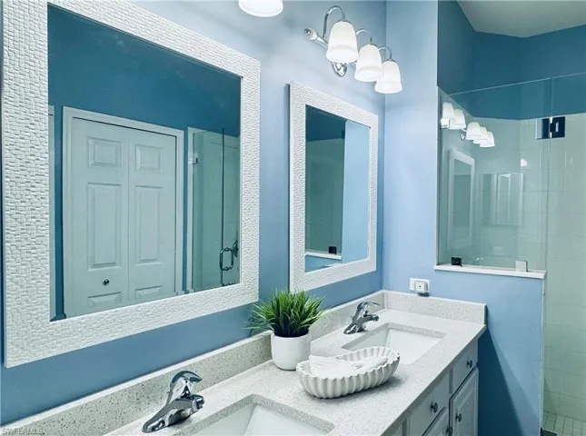 Full bath with a shower stall, double vanity, and a sink