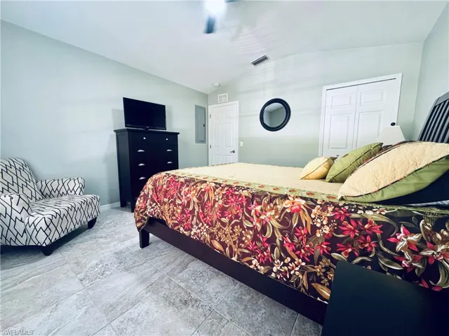 Bedroom with electric panel, baseboards, lofted ceiling, and a ceiling fan