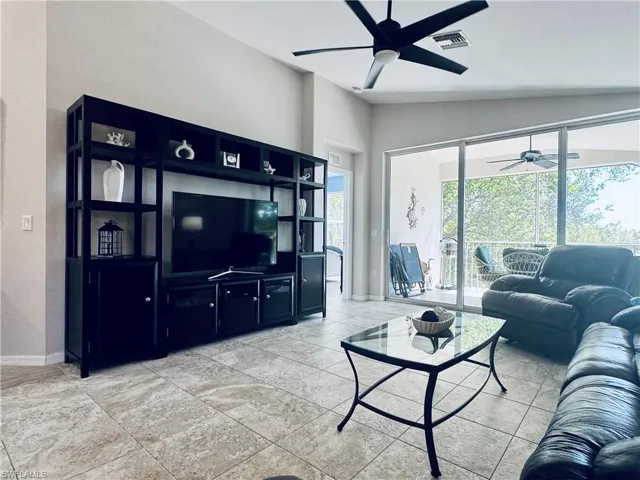 Living room with visible vents, lofted ceiling, baseboards, and ceiling fan