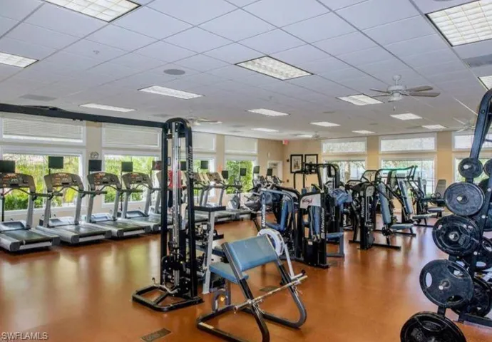 Gym with a wealth of natural light, a drop ceiling, and ceiling fan