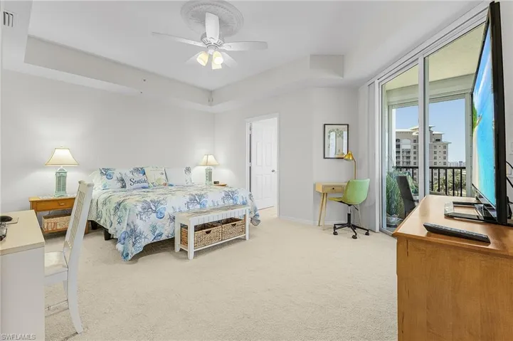 Bedroom with a raised ceiling, carpet flooring, access to exterior, and ceiling fan