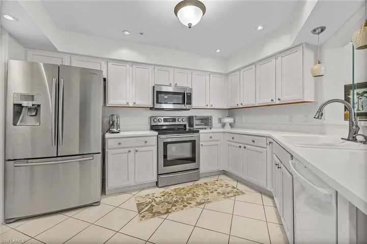 Kitchen featuring sink, hanging light fixtures, white cabinets, and appliances with stainless steel finishes