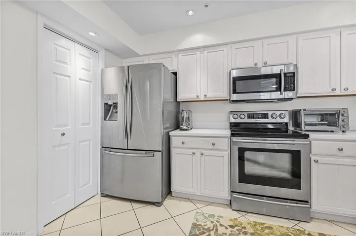 Kitchen featuring appliances with stainless steel finishes, light tile patterned floors, and white cabinets