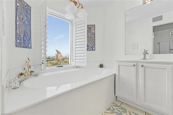 Bathroom with tile patterned flooring, vanity, and a bath