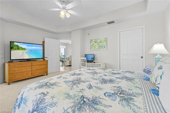 Bedroom featuring ceiling fan, a raised ceiling, and carpet floors