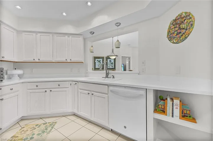 Kitchen with light tile patterned flooring, sink, dishwasher, pendant lighting, and white cabinets