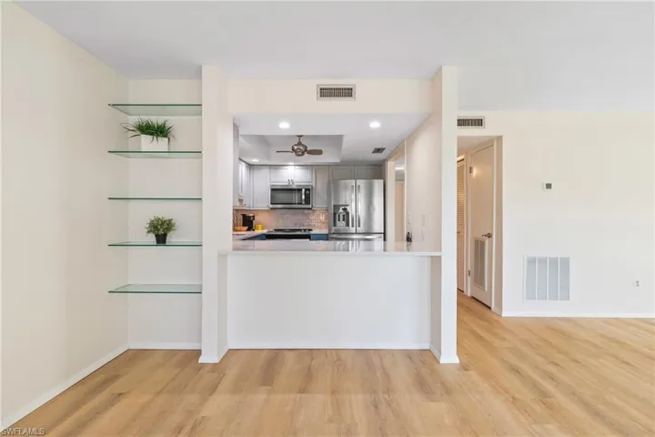 Kitchen featuring kitchen peninsula, appliances with stainless steel finishes, light wood-type flooring, and tasteful backsplash