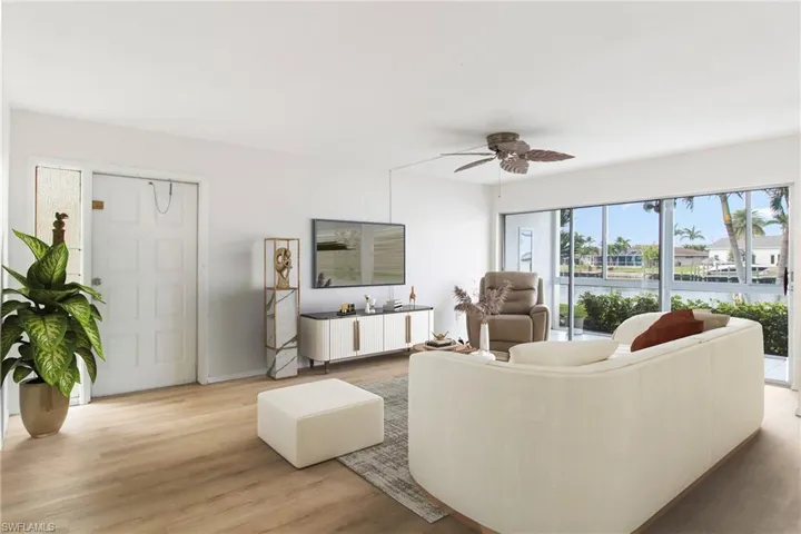 Living room with light wood-type flooring and ceiling fan virtually staged