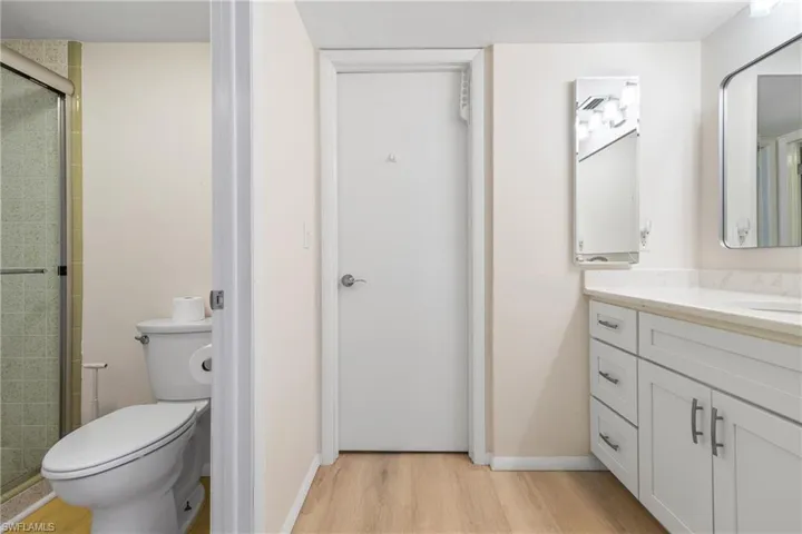 Bathroom featuring walk in shower, hardwood / wood-style floors, vanity, and toilet