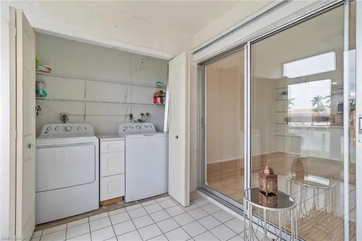 Washroom with separate washer and dryer and light tile patterned floors