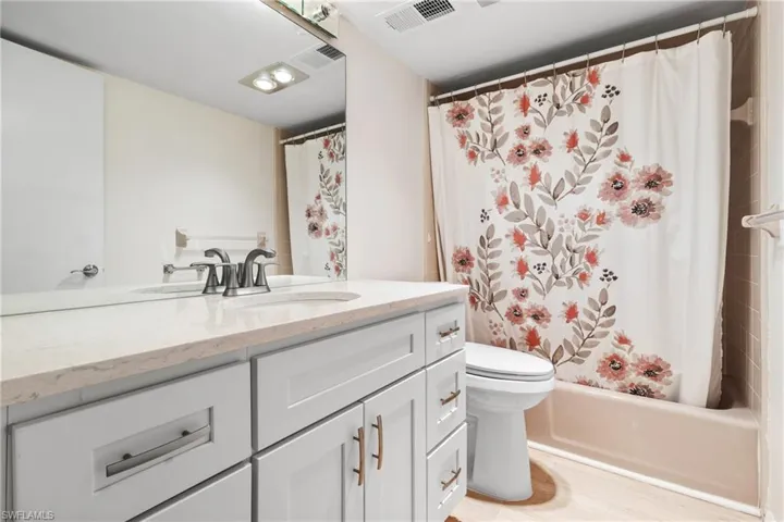 Full bathroom featuring vanity, toilet, and shower / bathtub combination with curtain