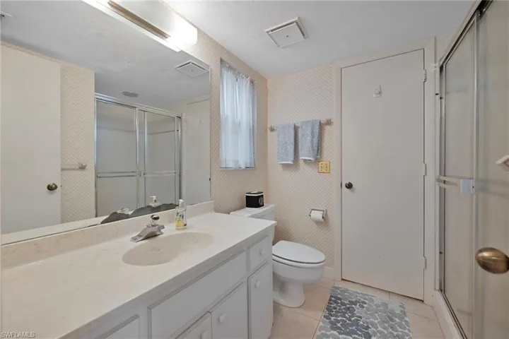 Bathroom featuring wallpapered walls, a shower stall, vanity, and light tile patterned floors