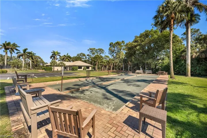 View of property's community with a lawn, a game area, a patio, and view of scattered trees