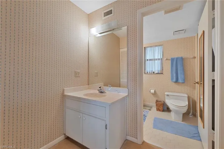 Bathroom featuring wallpapered walls and vanity