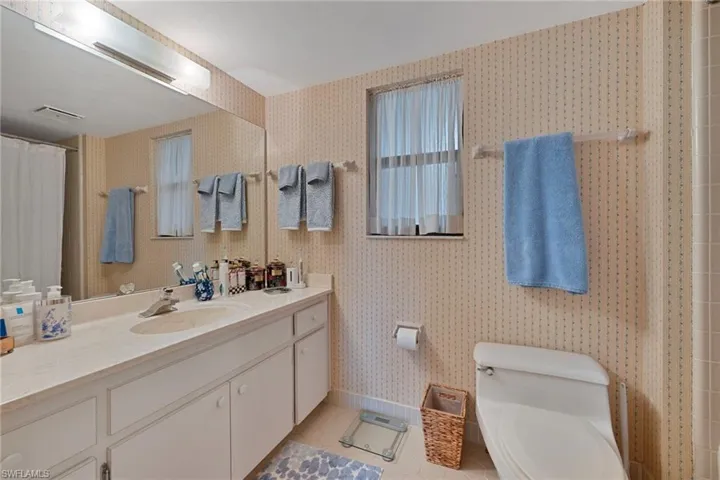Bathroom featuring vanity, light tile patterned floors, wallpapered walls, and a shower with curtain