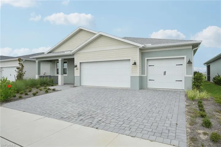 Ranch-style home with decorative driveway, a garage, covered porch, and stucco siding