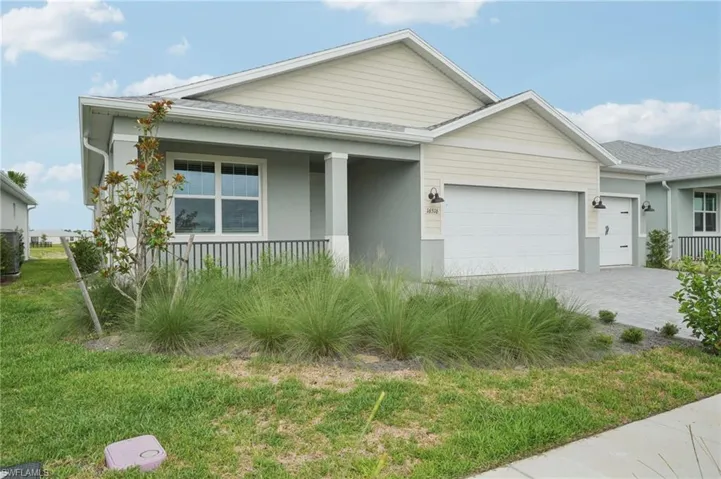 View of front of house with a garage, a porch, decorative driveway, and a front lawn