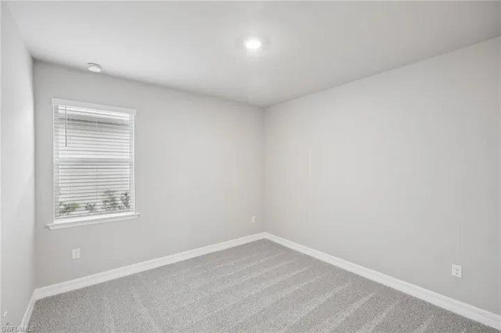 Unfurnished room featuring carpet floors, baseboards, and a smoke detector