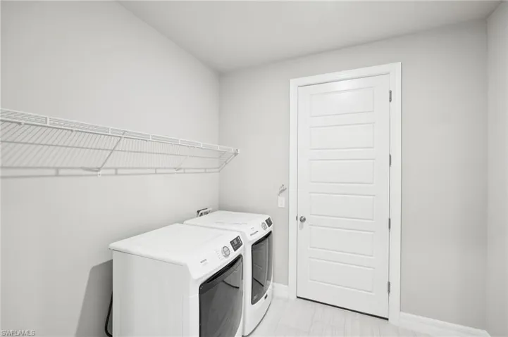 Washroom featuring independent washer and dryer and baseboards