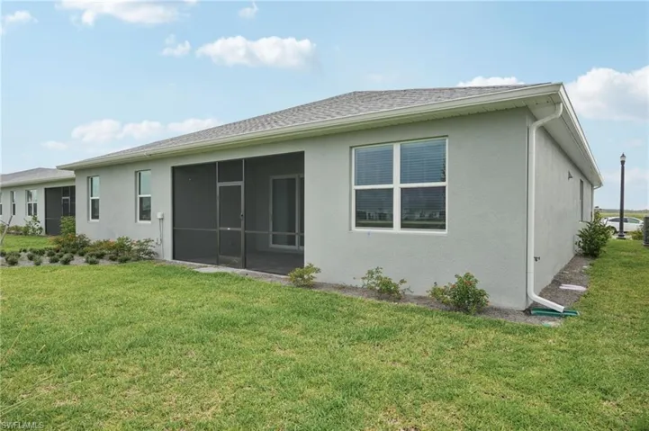 Back of house featuring a yard, a sunroom, and stucco siding