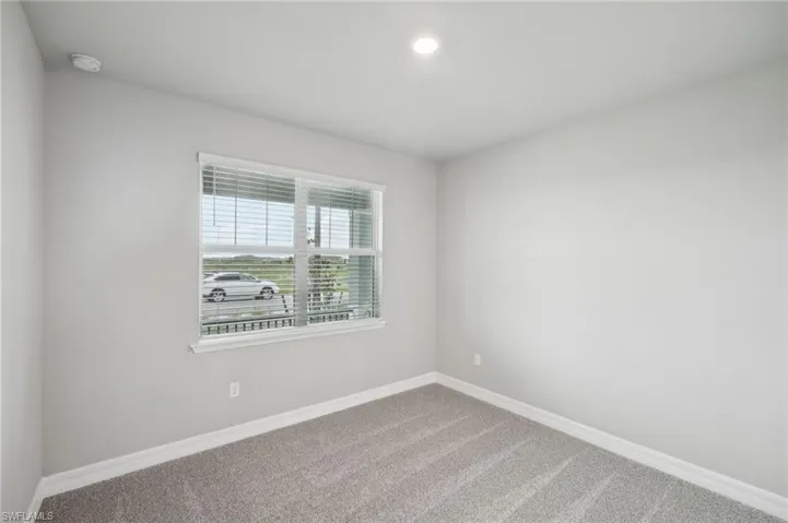 Carpeted empty room with a smoke detector, baseboards, and recessed lighting