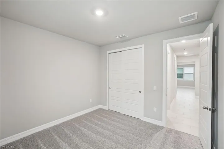 Unfurnished bedroom featuring recessed lighting, baseboards, carpet, and a closet