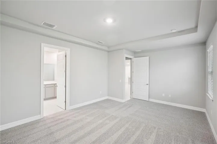 Unfurnished bedroom featuring light carpet, baseboards, connected bathroom, and recessed lighting