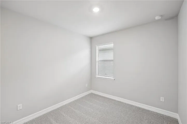 Unfurnished room featuring carpet flooring, baseboards, and a smoke detector