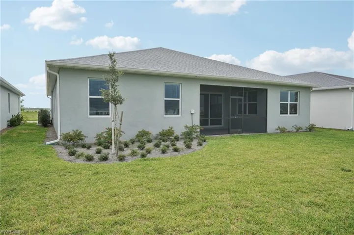 Rear view of house featuring a yard, a sunroom, and stucco siding