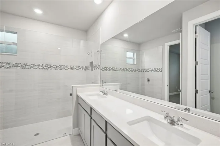 Bathroom featuring walk in shower, double vanity, and recessed lighting