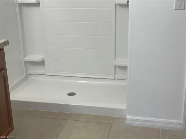 Bathroom featuring light tile patterned flooring, a stall shower, and vanity