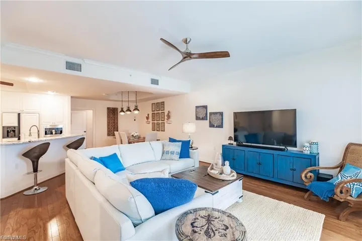 Living area with ceiling fan, wood finished floors, and crown molding