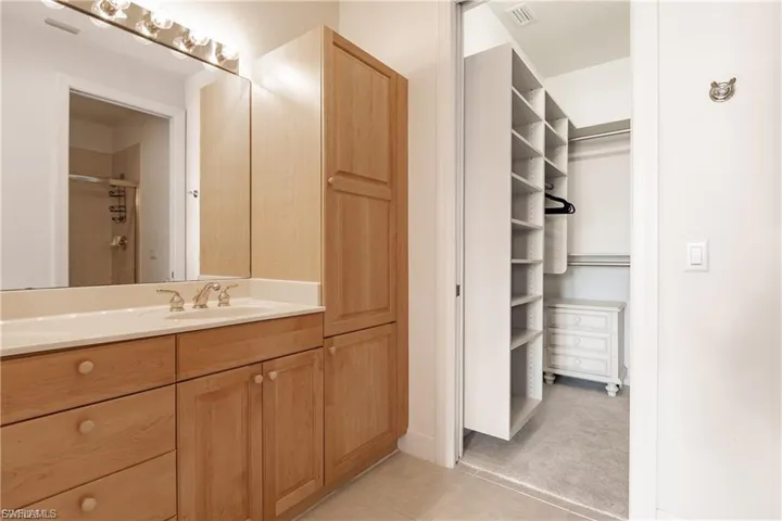 Bathroom featuring vanity, a stall shower, a walk in closet, light tile patterned floors, and light carpet