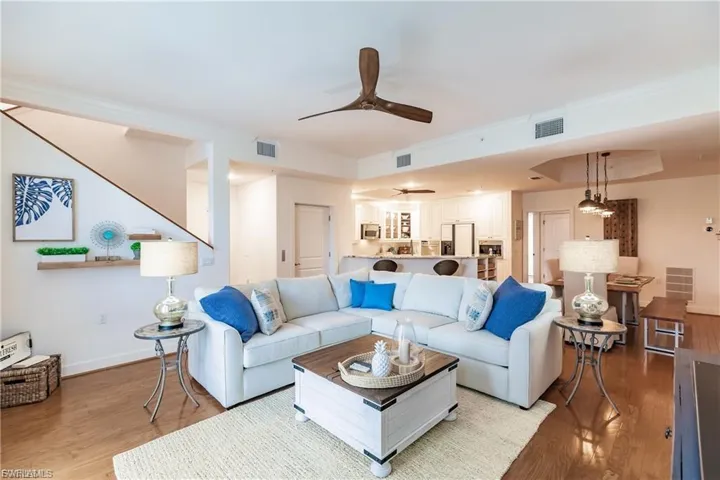 Living room featuring wood finished floors, ceiling fan, and a tray ceiling