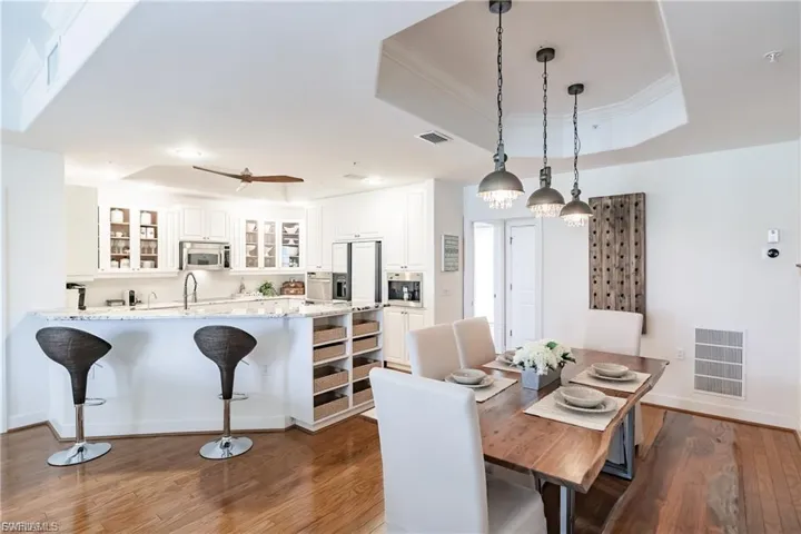 Dining space featuring a raised ceiling, light wood-style flooring, and crown molding