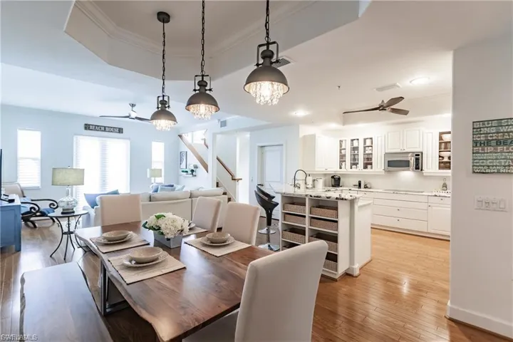 Dining room featuring a tray ceiling, a ceiling fan, a chandelier, light wood-type flooring, and ornamental molding