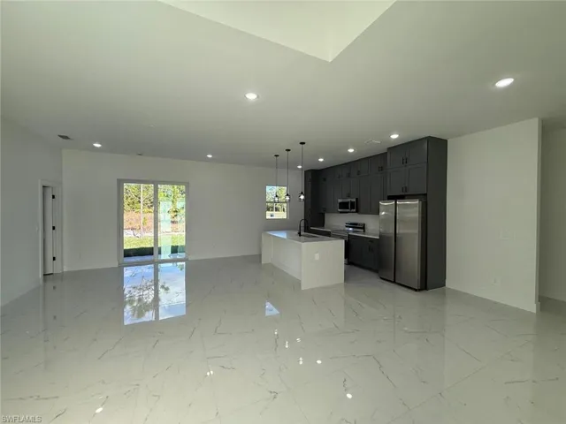 Kitchen featuring open floor plan, appliances with stainless steel finishes, pendant lighting, a center island with sink, and recessed lighting