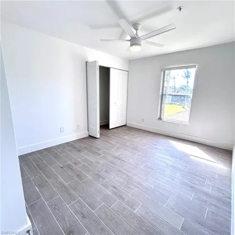 Unfurnished bedroom featuring a ceiling fan, wood finished floors, baseboards, and a closet