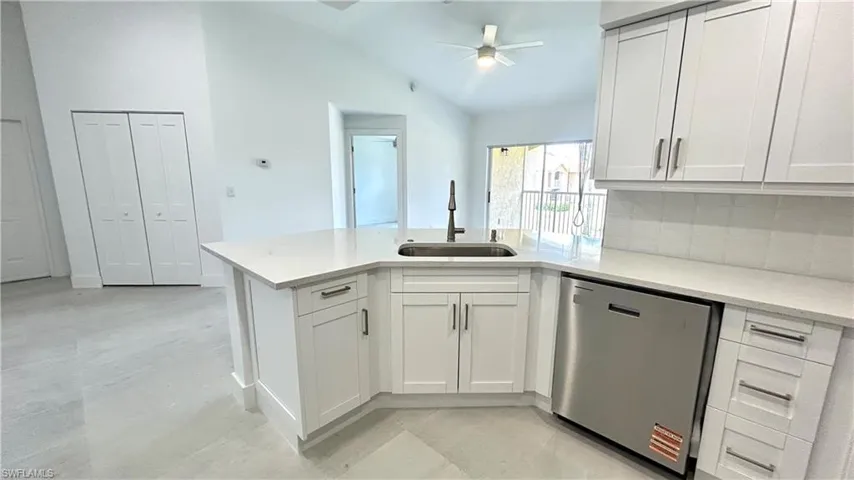 Kitchen featuring dishwasher, a sink, a peninsula, lofted ceiling, and light countertops
