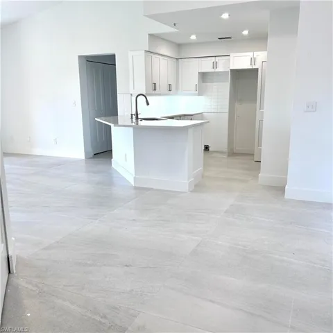 Kitchen with a sink, baseboards, a peninsula, and white cabinets