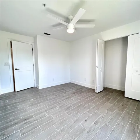 Unfurnished bedroom with visible vents, baseboards, wood tiled floor, a closet, and a ceiling fan
