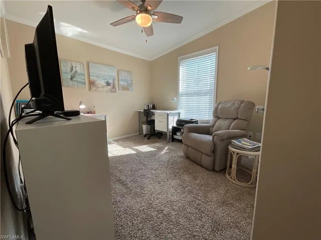 Carpeted office space with lofted ceiling, ceiling fan, and crown molding