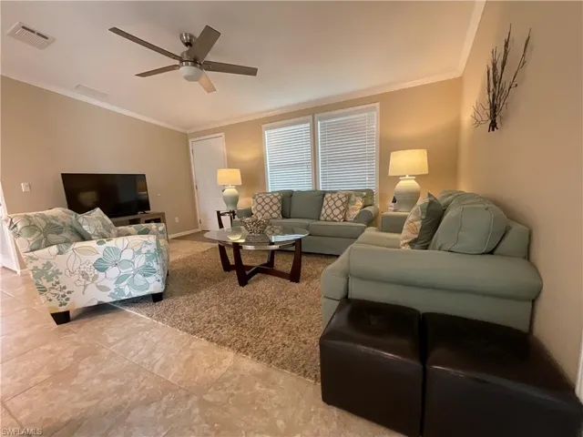 Tiled living room featuring ceiling fan and crown molding