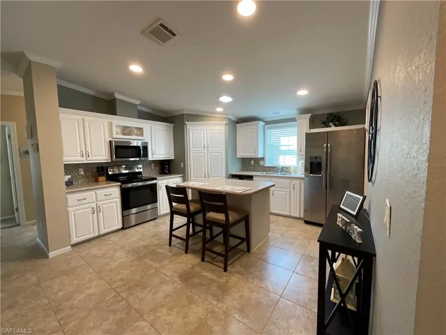 Kitchen with white cabinets, a center island, and stainless steel appliances