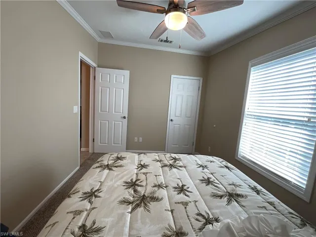 Unfurnished bedroom with carpet, ceiling fan, and ornamental molding