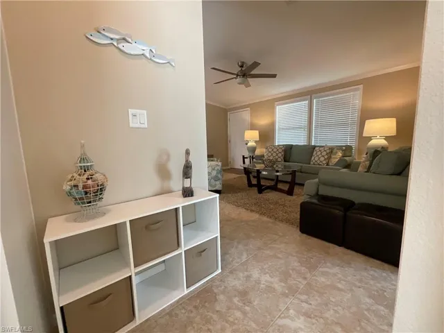 Tiled living room featuring ceiling fan and crown molding