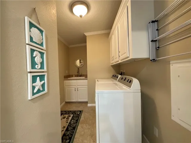Laundry room featuring cabinets, a textured ceiling, crown molding, sink, and independent washer and dryer