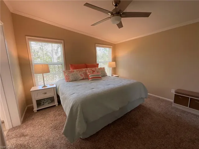 Bedroom with multiple windows, carpet flooring, ceiling fan, and lofted ceiling