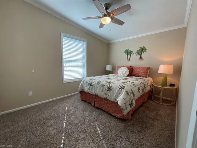 Carpeted bedroom featuring ceiling fan and crown molding